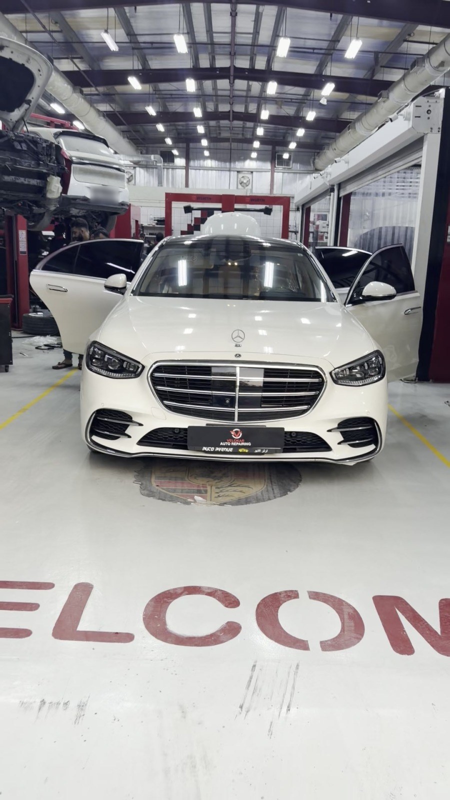 White Mercedes S-Class parked at the entrance of the Velokar workshop, with the welcome sign on the floor