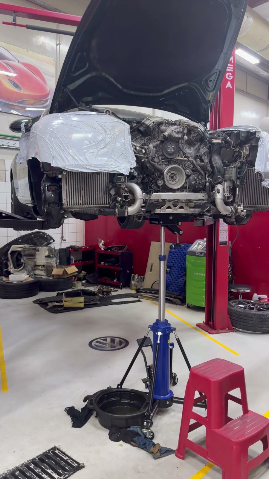 Engine and front assembly lowered on a transmission jack under a car raised on a two-post lift at Velokar