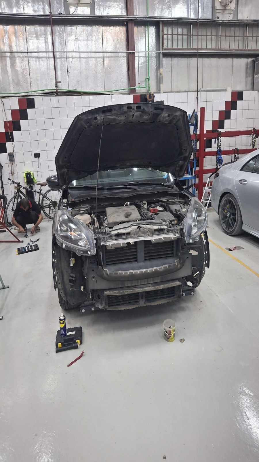 Car with the bonnet open and the front end stripped for repair in the Velokar workshop, Al Quoz