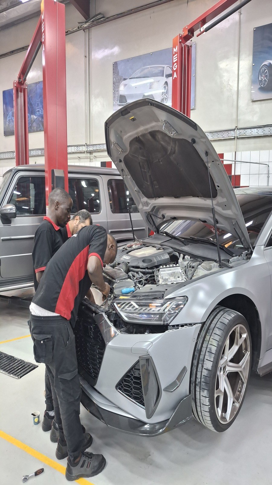 Two Velokar technicians working in the engine bay of a Nardo Grey Audi in Al Quoz, Dubai