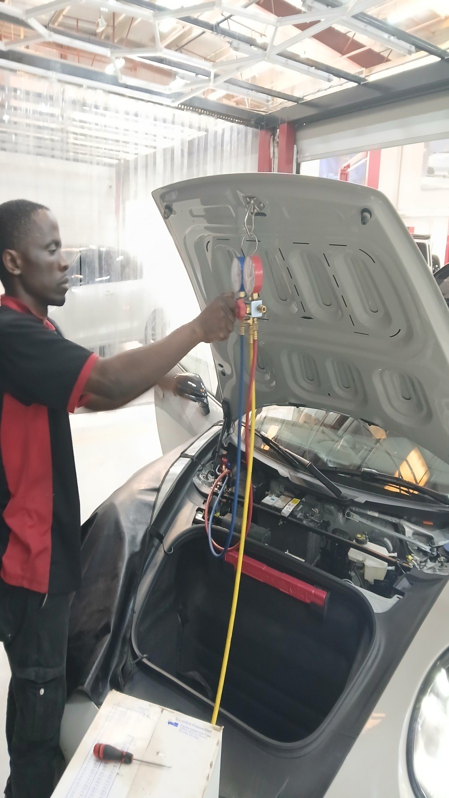 Velokar technician connecting the AC service hoses to the front of a white car with the bonnet raised