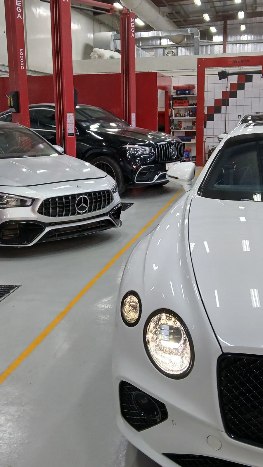 White Bentley Continental GT and other customers’ cars lined up in the service bay at Velokar in Al Quoz, Dubai