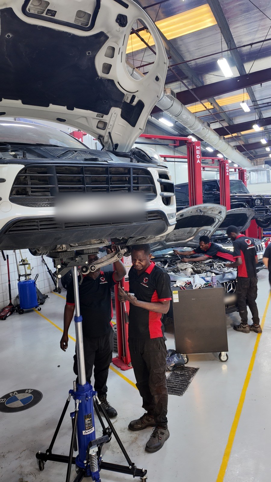 فنّيان من فيلوكار يعملان تحت مرسيدس SUV مرفوعة على رافعة بعمودين مع رافعة جير