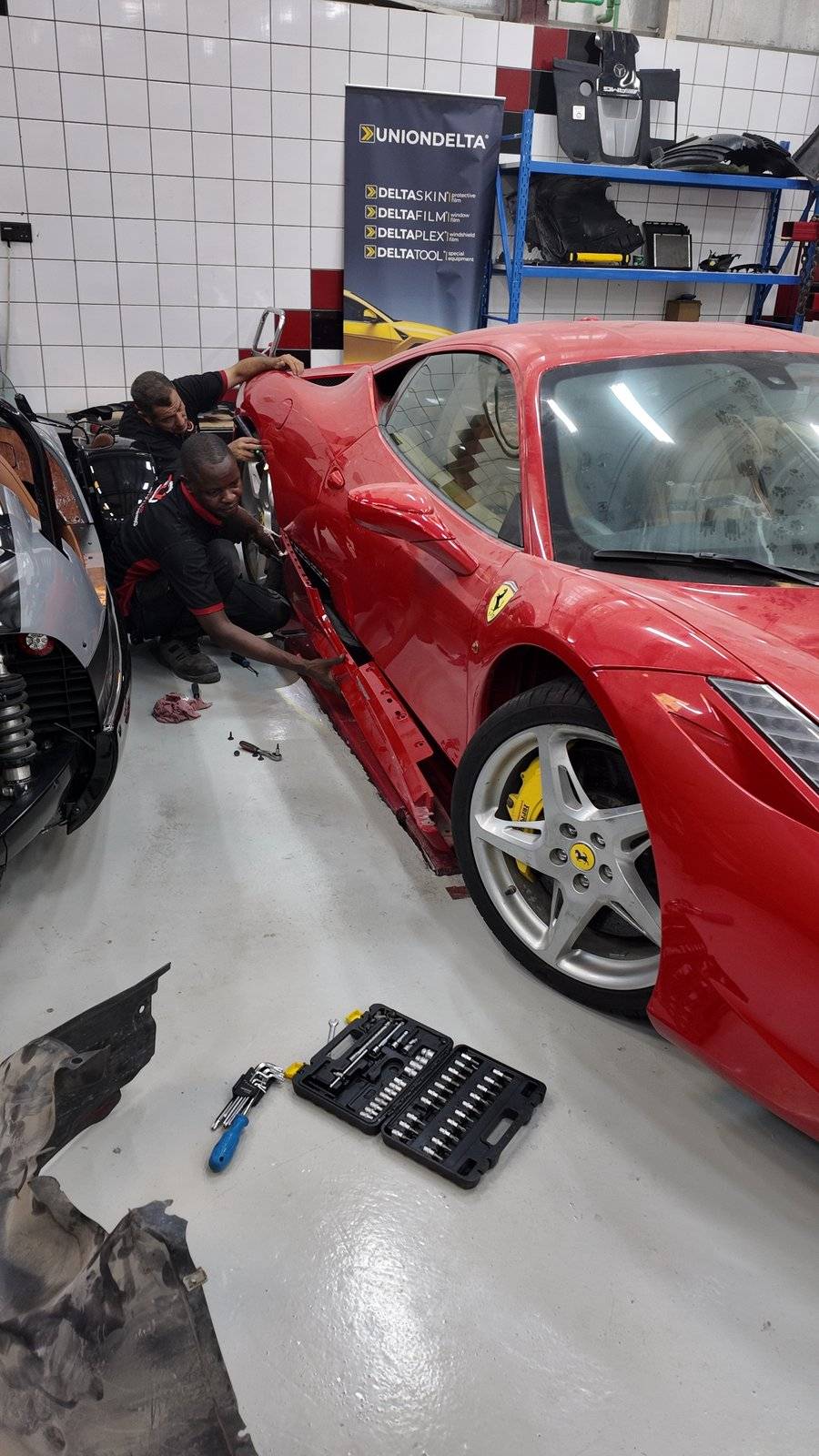 Velokar technicians working on the rocker panel of a Ferrari 458