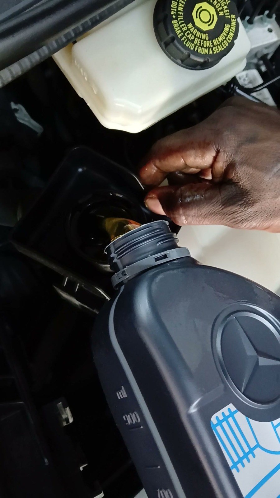 Engine oil to the car-maker’s specification being poured from its container into a Mercedes engine at Velokar