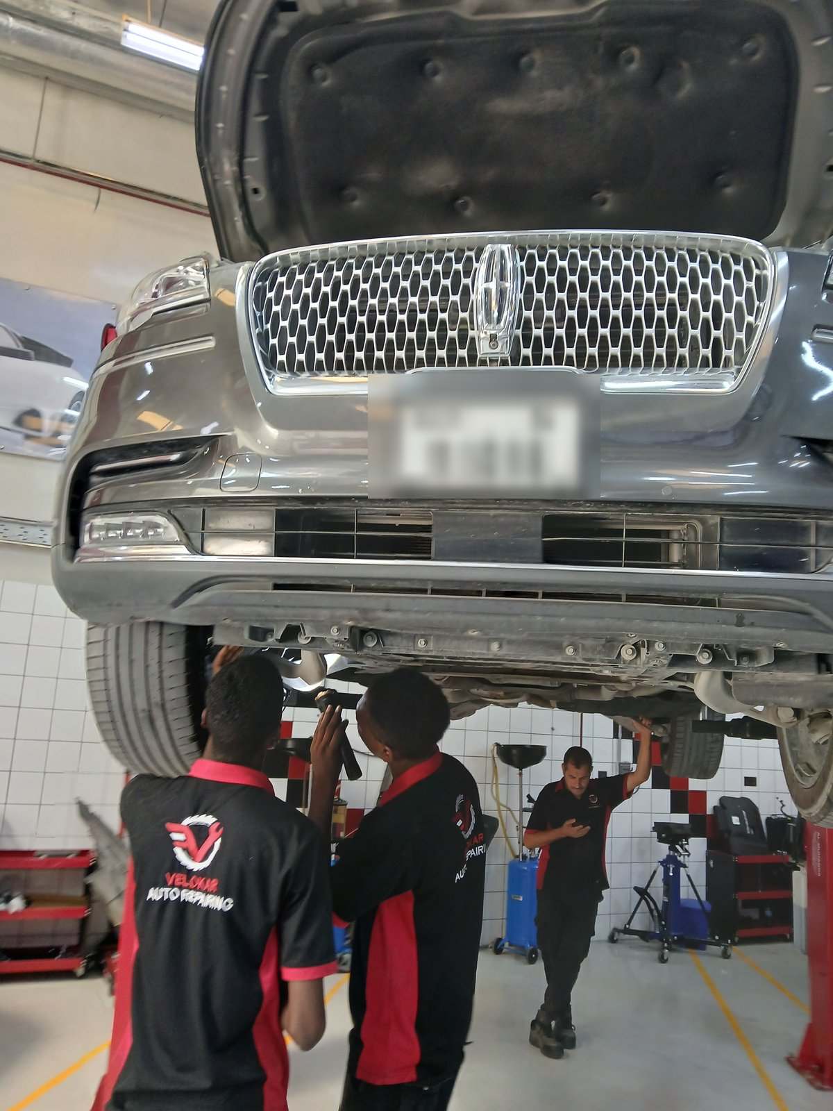Lincoln Aviator on the lift at Velokar with technicians inspecting the underbody