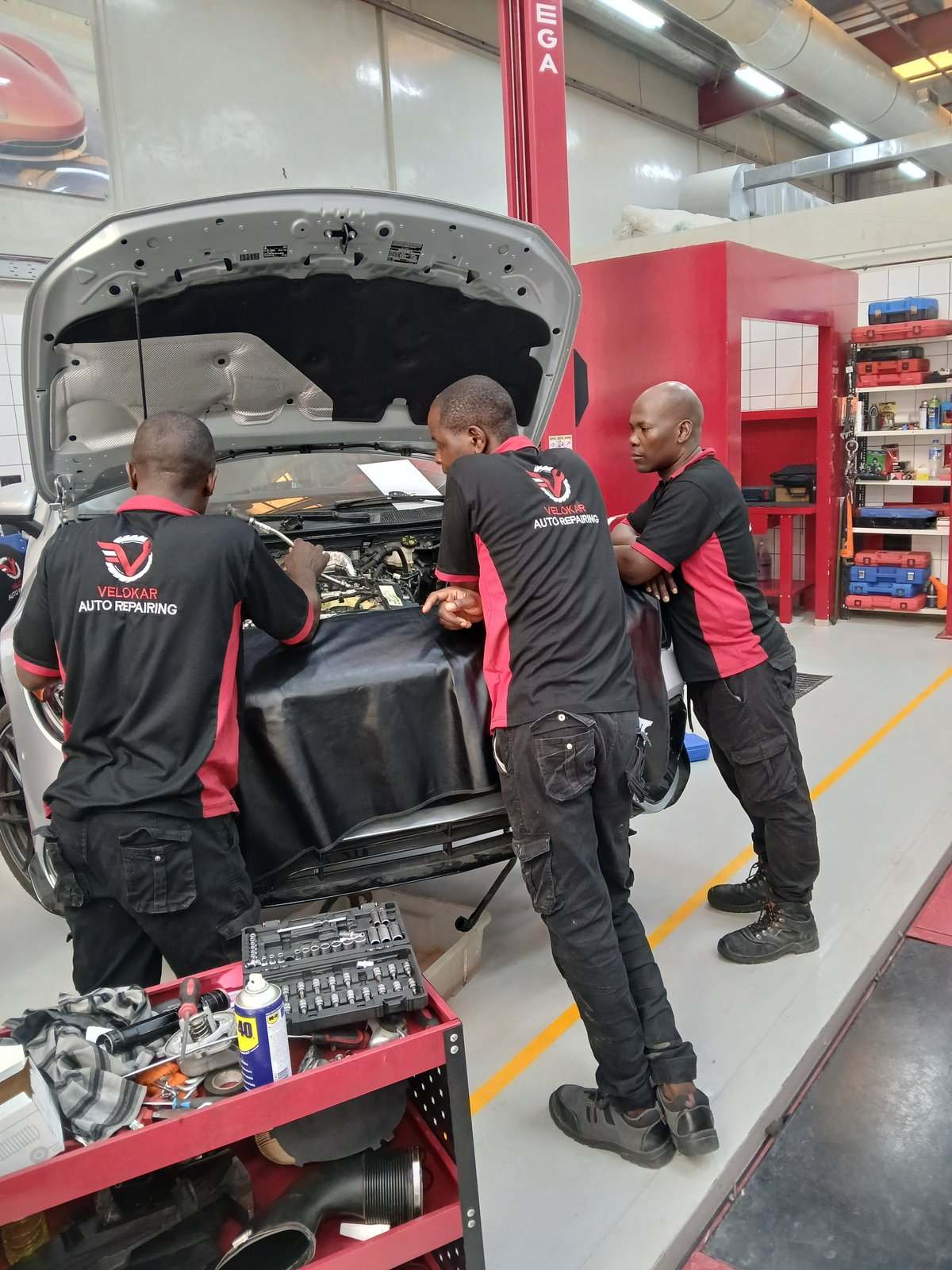 Velokar technicians working together over a Lincoln engine bay