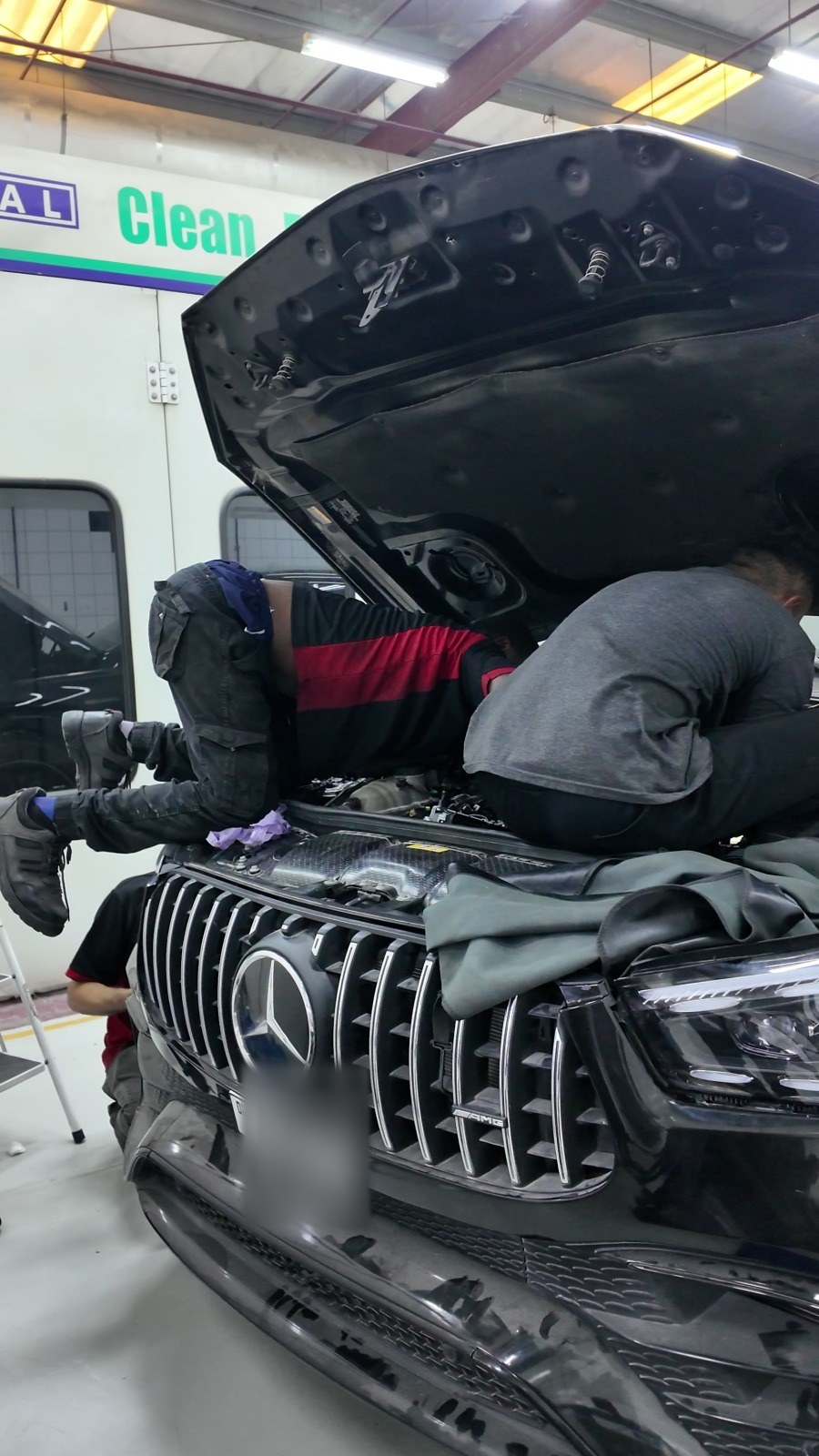 Two Velokar technicians working at the front of a black Mercedes-AMG SUV