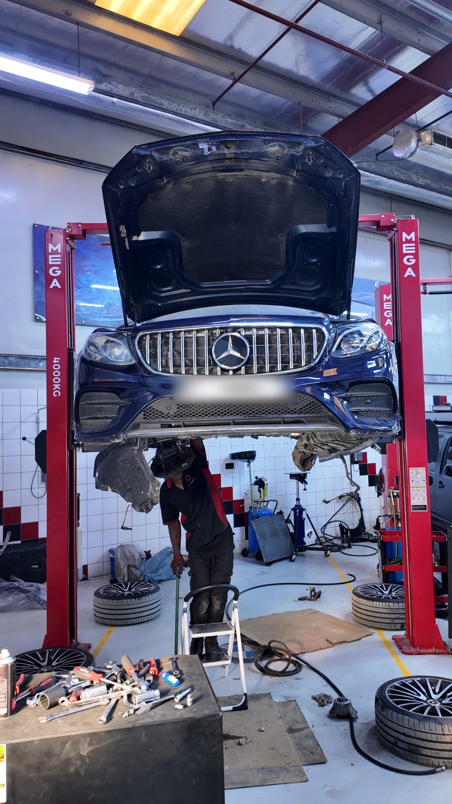 Mercedes-AMG raised on a two-post lift while a Velokar technician works underneath