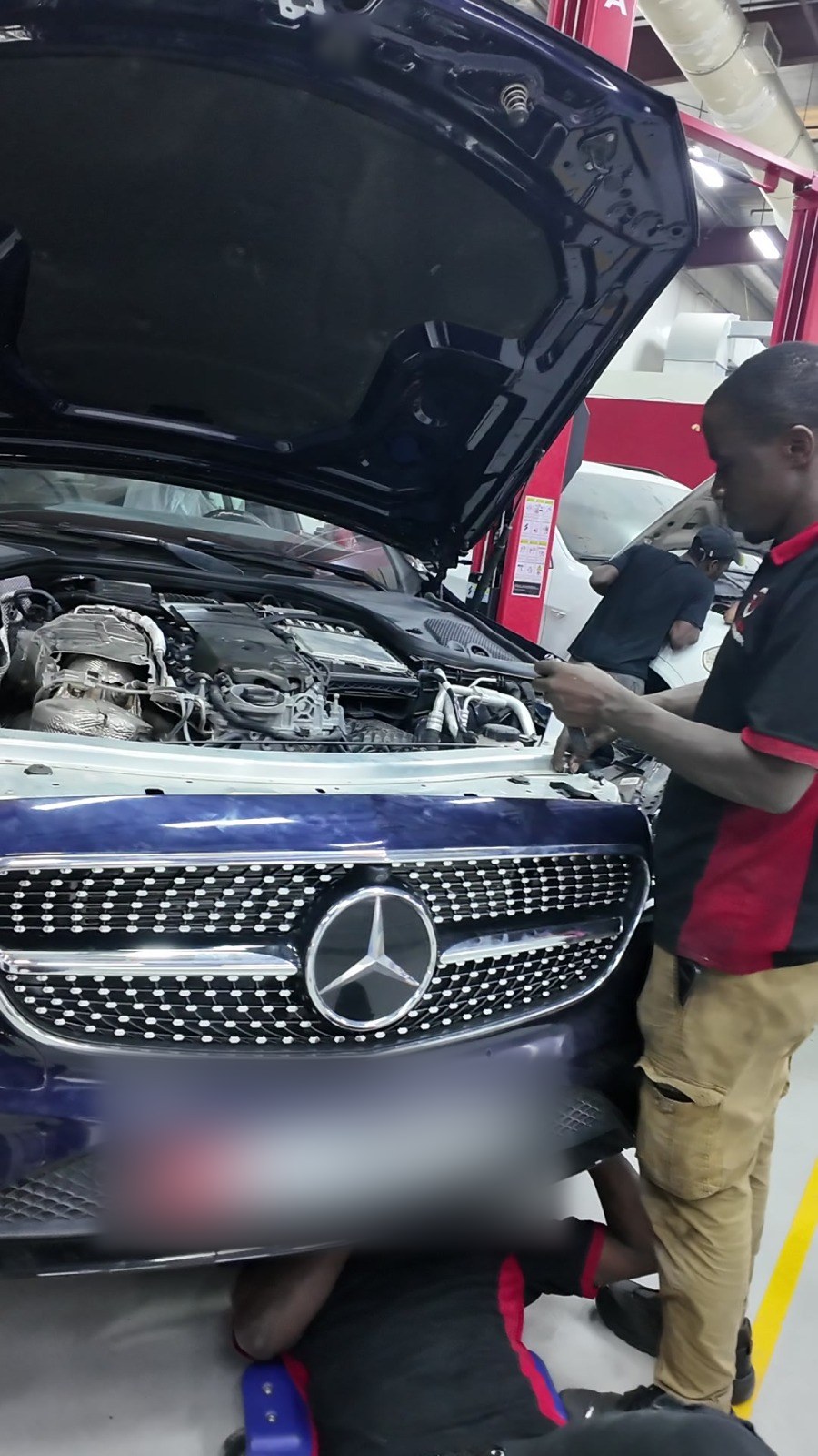 Mercedes E-Class with the bonnet open and Velokar technicians at work