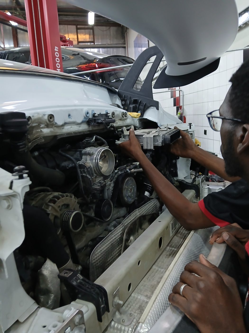 Velokar technician working on a Porsche Panamera engine with the front end removed