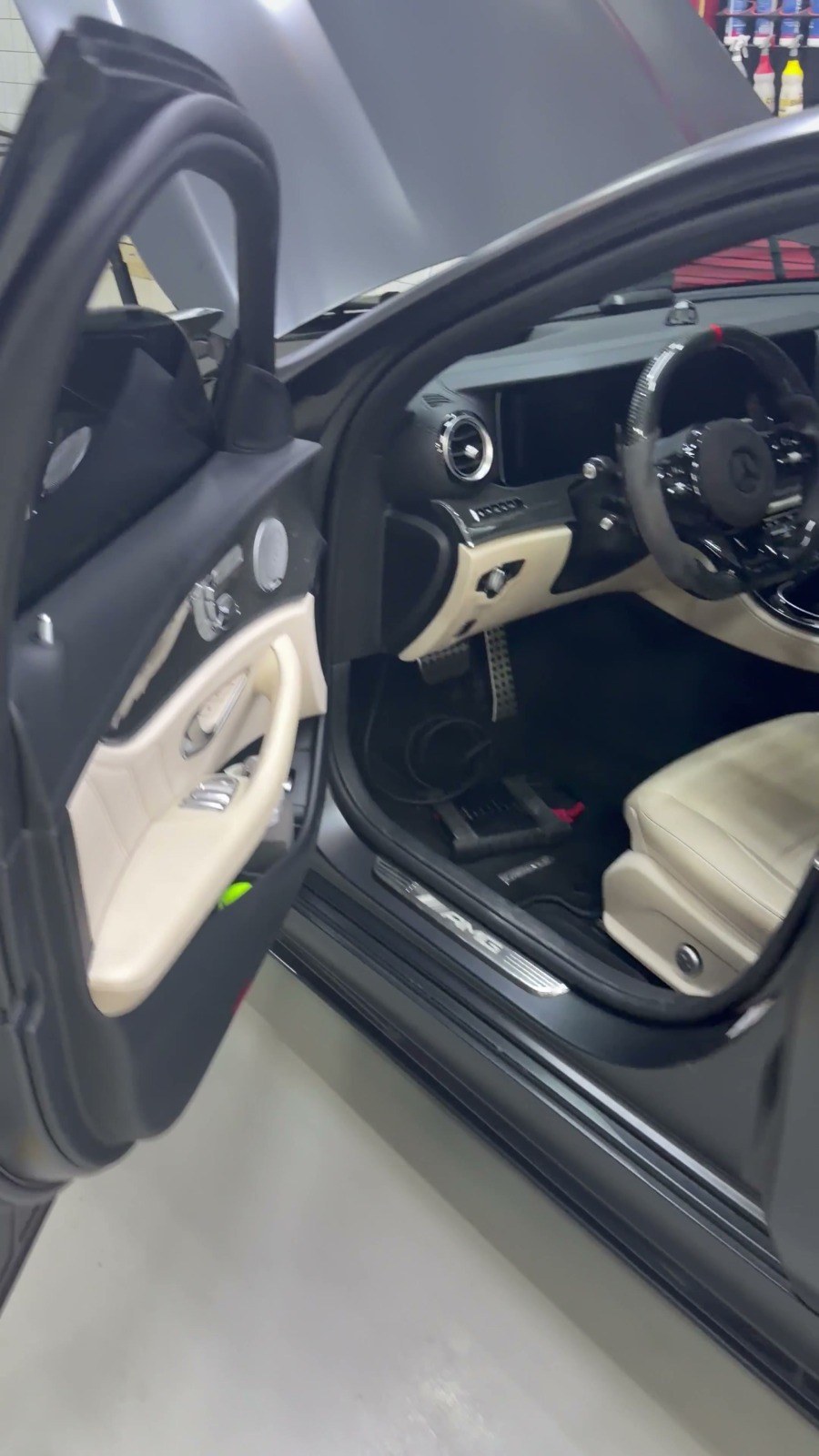 Open driver's door of a Mercedes showing the seat, steering wheel and door trim, in the Velokar workshop