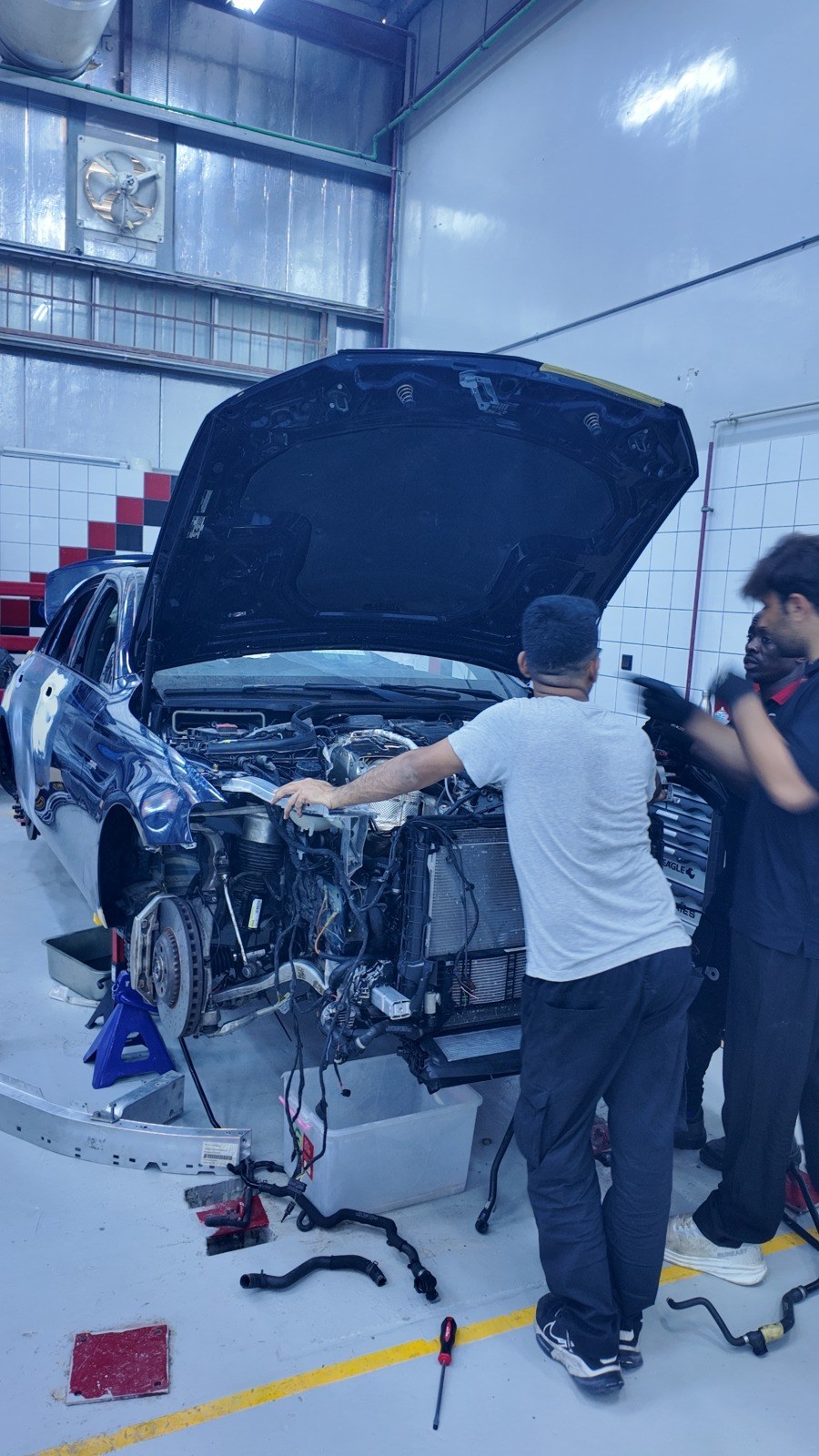 Two technicians working on a car with the front bumper removed in the Velokar workshop, Al Quoz Industrial 3